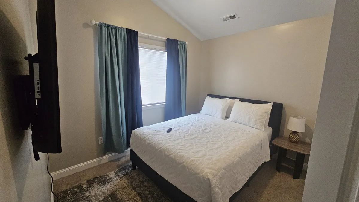 A serene bedroom scene with a comfortable bed, curtains softly diffusing morning light, a nightstand, and a lamp. The setting emphasizes a peaceful, restful environment perfect for reading or unwinding.