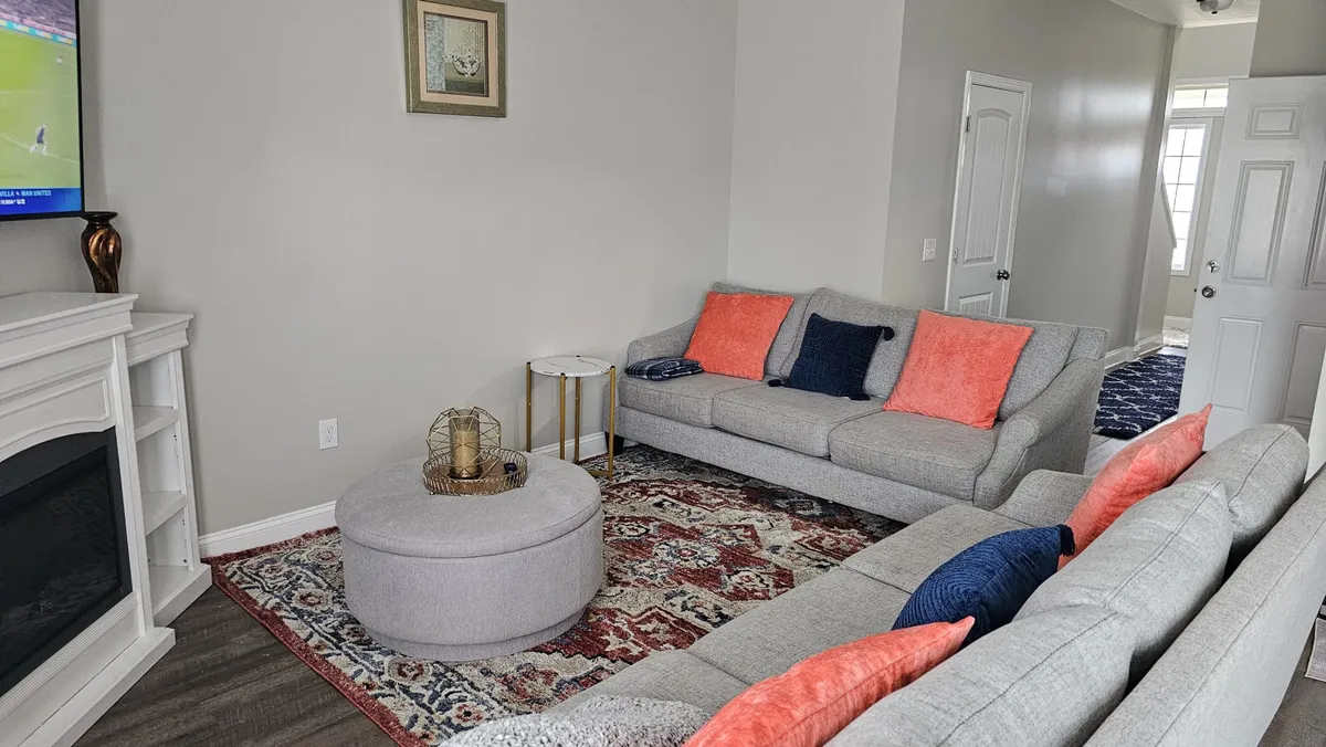 This cozy living room interior features a plush sofa, a coffee table, a television, and a soft rug, all arranged for comfort and togetherness. The space is designed for memorable movie nights, celebrations, or simply unwinding after a day of adventure.